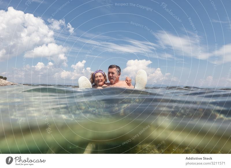 Mature couple swimming together in fresh water vacation crystal sea ocean retired greece halkidiki floating sunny holiday nautical relaxing wave summer elderly