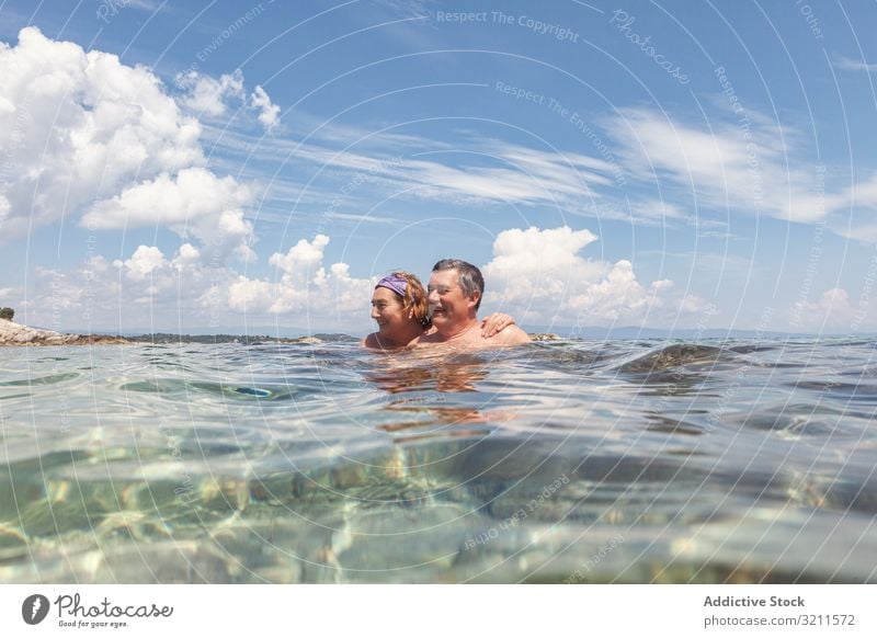 Mature couple swimming together in fresh water vacation crystal sea ocean retired greece halkidiki floating sunny holiday nautical relaxing wave summer elderly