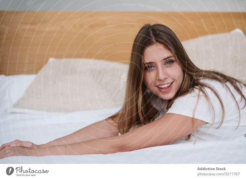 Beautiful woman in white t-shirt relaxing on bed and looking at camera destination adventure vacation young female person beautiful attractive pretty barefoot