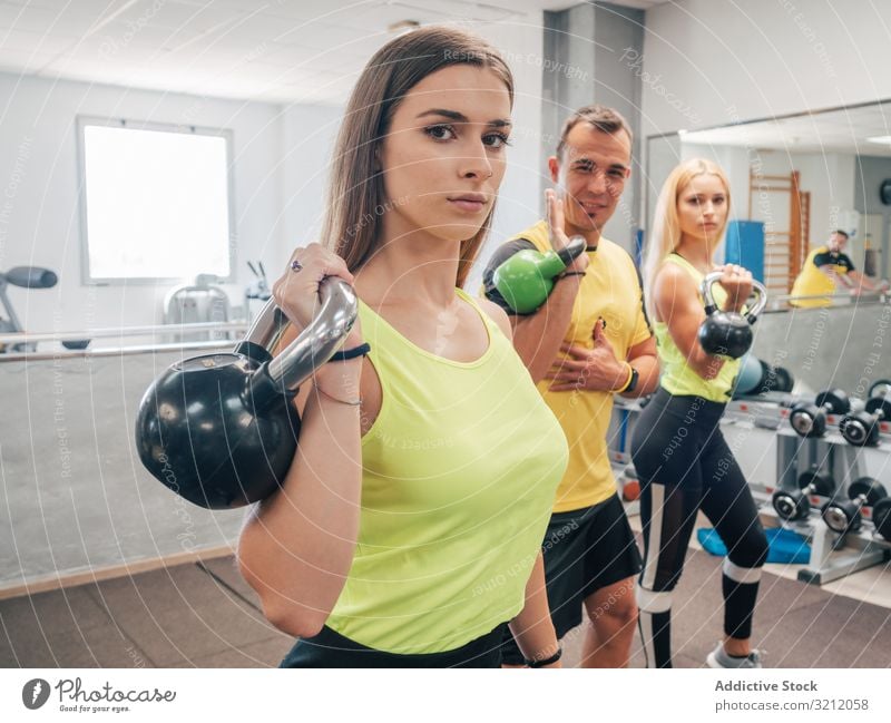 Athletes with kettlebells at the gym athlete class exercise workout lift sport strength above head power coach group fitness wellbeing vitality heavy physical