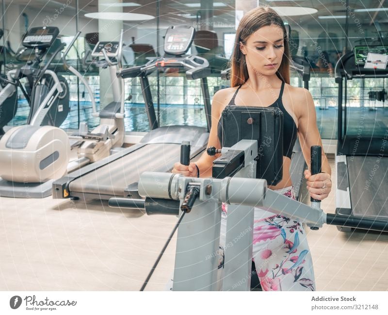 Strong female on row machine exercise gym workout sport athlete woman strength power back modern training fit young fitness healthy wellness wellbeing vitality