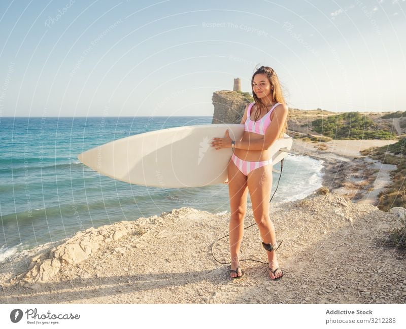 Woman raising surfboard high staying on seashore woman beach swimsuit car tanned seaside vacation slim sunbath active sport lifestyle summer attractive female
