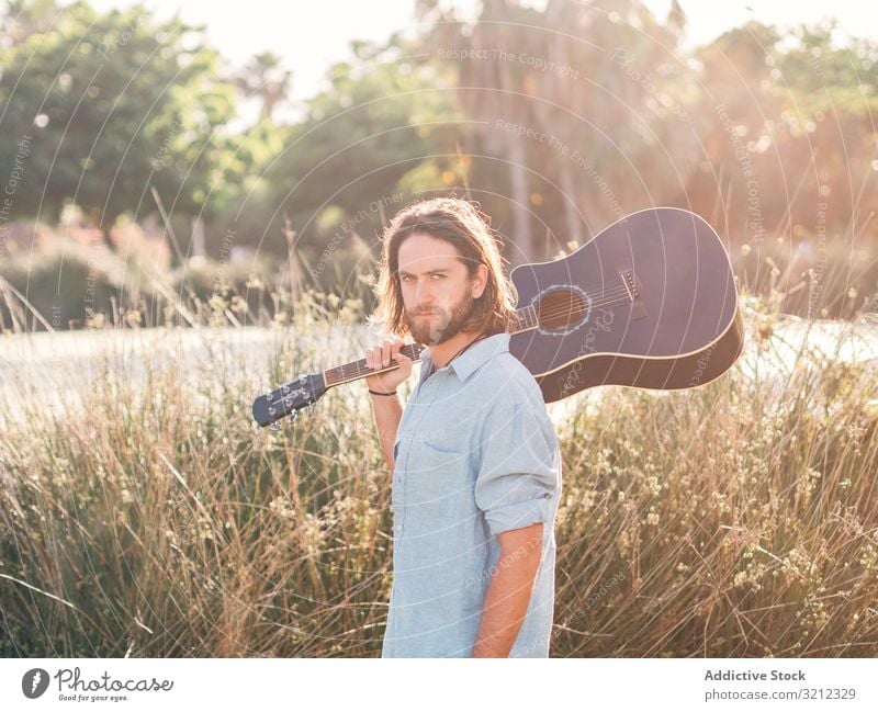 Hipster man in jungle with guitar hipster musician playing adventure trip summer lifestyle pensive male acoustic young entertainment leisure practice nature