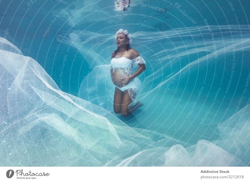 Pregnant woman in wreath and white dress underwater pregnant floral natural purity harmony innocent sensual mother peace female love adult belly hand motherhood