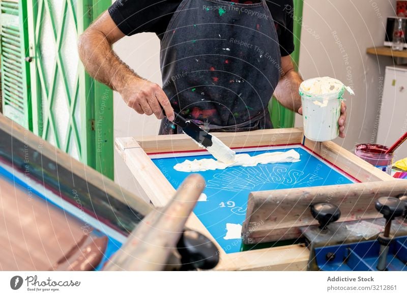 Male artist creating print on t-shirt master screen printing silkscreen serigraphy workshop hobby easel dirty apron style paint modern prepare drawing male
