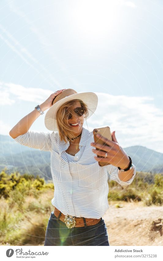 Young girl smiling while looking at her smart phone woman happy sunset using people mobile hat sunglasses young smartphone caucasian person portrait holding
