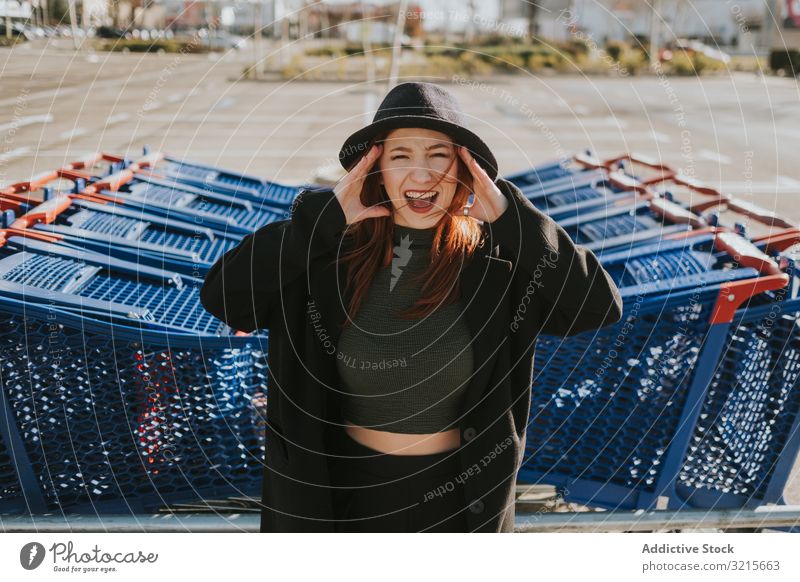 Woman screaming in parking lot with shopping carts woman attractive young beautiful casual smart modern joy excited redhead female pretty pleasure stylish