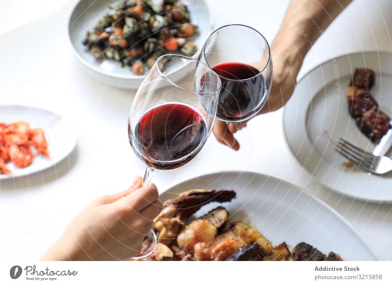 Couple cheering with red wine glass dinner celebration alcohol drink beverage food party adult people couple eating toasting drinking delicious tasty crystal