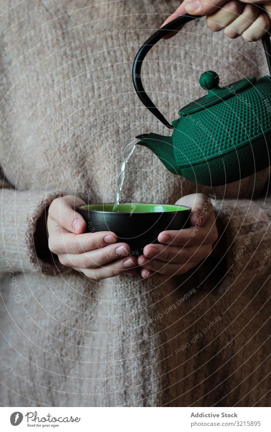 Person pouring tea to cup in hands of woman knitted teapot relaxation drink hot beverage sweater water kettle liquid ceramic holding lady green refreshment