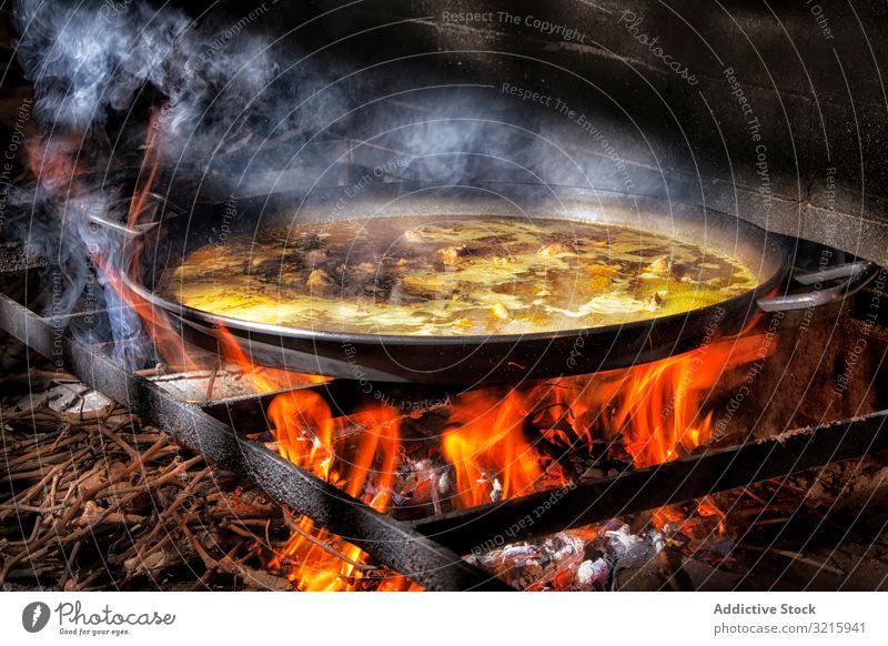 Process of cooking paella on fire rice process cuisine adding spanish traditional food chicken broth flame iron big wood heat hot brick stove dinner seafood