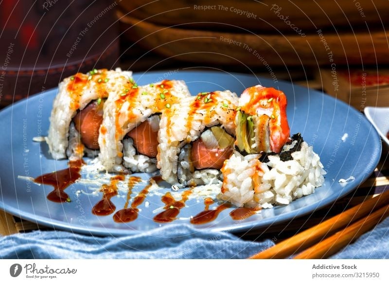 Tasty sushi poured with sauce on blue plate green tasty gastronomy served fish delicious appetizing restaurant asian food dinner salmon meal seafood dish fresh
