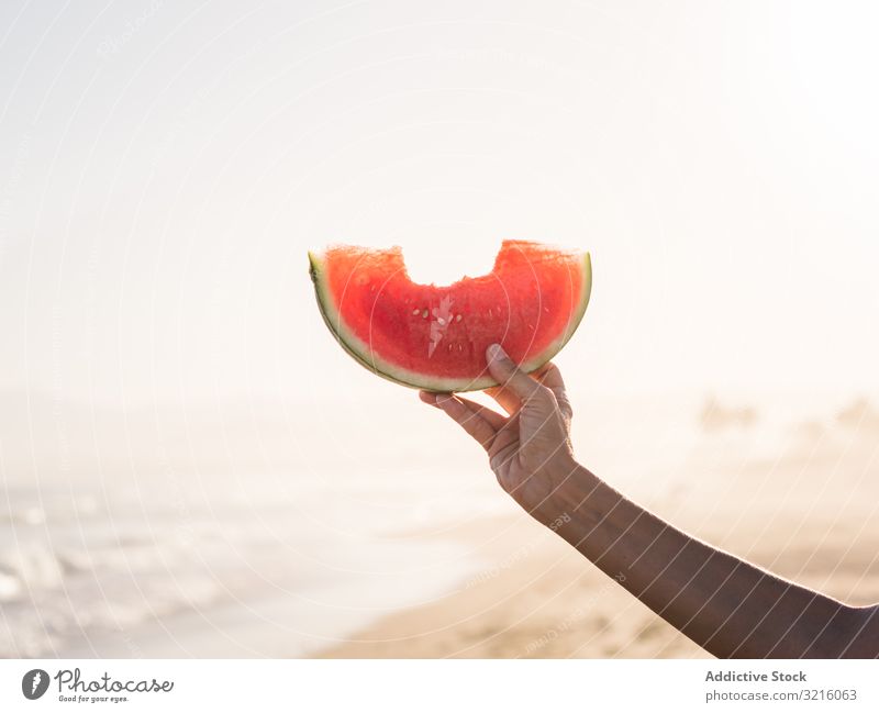 Hand of a person holding red watermelon fruit food beach sandy juicy tasty snack summer eating seaside lifestyle vacation pleasure enjoyment travel relaxation