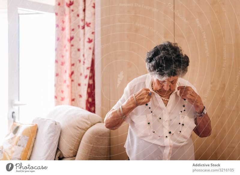 Aged woman standing near armchair at home aged grandmother wisdom attention grandparent generation senior elderly female wrinkle granny gray haired pensioner