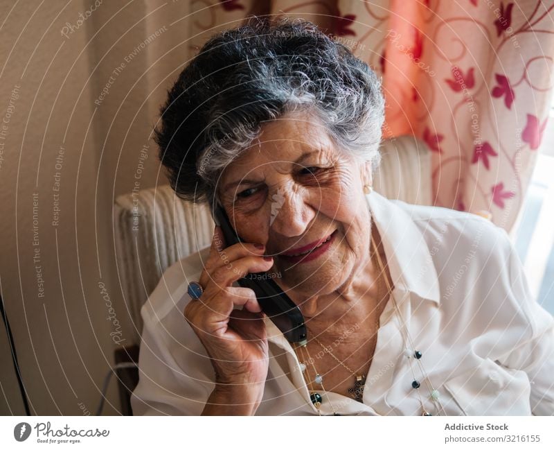 Cheerful elderly woman talking on cell phone at home aged mobile phone grandmother experience wisdom modern conversation attention grandparent generation senior