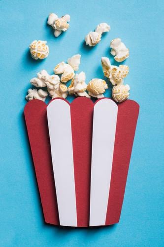 Silhouette of a popcorn box made of cardboard with real popcorn art cinema collage colorful composition concept conceptual craft creativity disposable flat lay