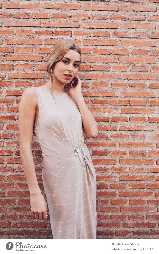 Portrait of casual young woman attractive portrait dress leaning brick wall lifestyle lady stylish pretty trendy person caucasian modern urban posing confident
