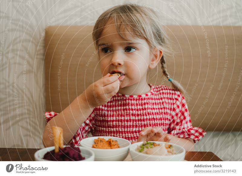 Girl eating with hand assorted food at table girl bowl gourmet homemade organic nutrition tasty refreshing raw adorable delicious yellow holiday innocence