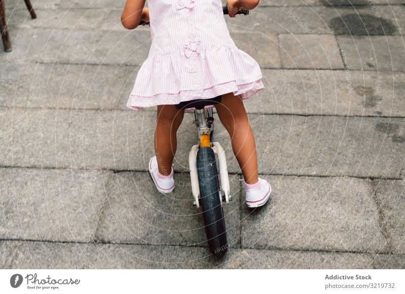 Girl riding on bicycle in narrow street smiling bike summer girl happy fun sport city cheerful day active childhood urban cyclist holiday lifestyle joyful dress