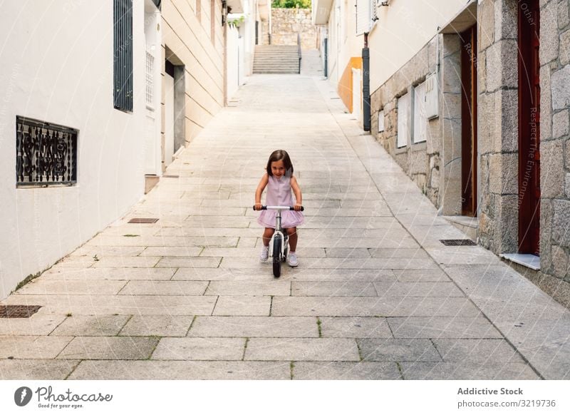Girl riding on bicycle in narrow street smiling bike summer girl happy fun sport city cheerful day active childhood urban cyclist holiday lifestyle joyful dress