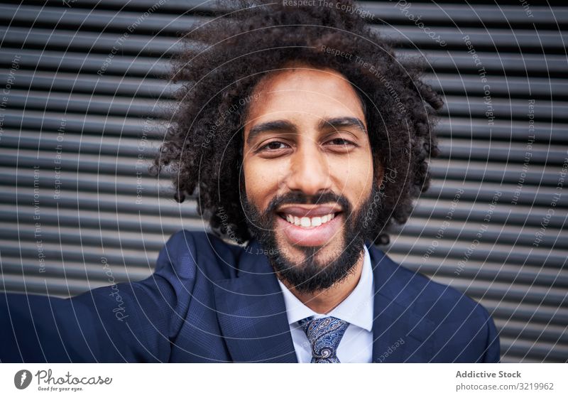 Joyful ethnic man taking selfie and smiling modern businessman formal african black smartphone wall smile happy afro cheerful african american office suit curly