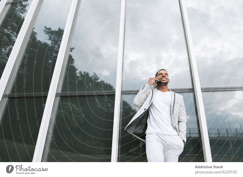 Elegant black man talking smartphone leaning building business architecture suit professional ethnic exterior african surfing corporate using futuristic work