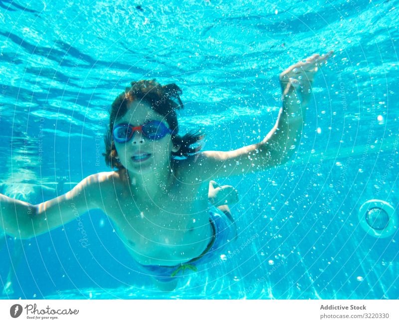 Funny boy swimming underwater looking at camera pool funny grimace breath hold child cheerful playful summer childhood dive swimwear vacation bubble recreation
