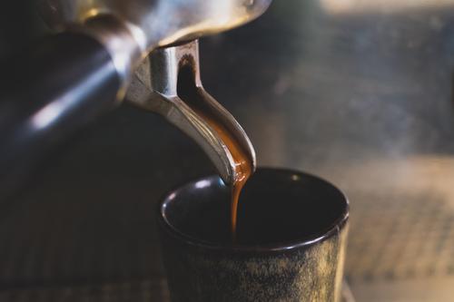 Espresso runs from a portafilter coffee machine into an espresso cup Coffee To enjoy screen carrier machine Coffee maker Detail Close-up coffee preparation