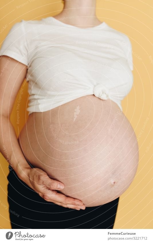 Pregnant woman showing her baby belly - neutral background Feminine Woman Adults 1 Human being 18 - 30 years Youth (Young adults) 30 - 45 years Happy Skin