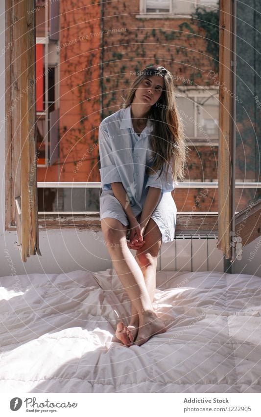 Woman sitting on window sill woman pensive bed tender bedroom thoughtful home calm sensual attractive female apartment casual young beautiful pretty upset