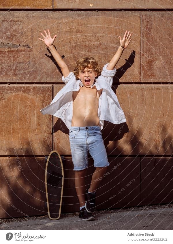Cheerful boy with hands up near skateboard child skatepark lifestyle cheerful yell sport leisure hobby young childhood cool interest summer sunny careful active