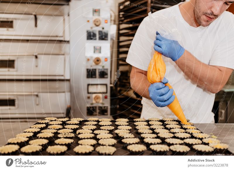 Crop baker filling pastry cases with jelly confectioner bakery squeeze tart bag kitchen sweet cuisine food dessert culinary tasty delicious yummy jam glove