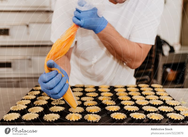 Crop baker filling pastry cases with jelly confectioner bakery squeeze tart bag kitchen sweet cuisine food dessert culinary tasty delicious yummy jam glove