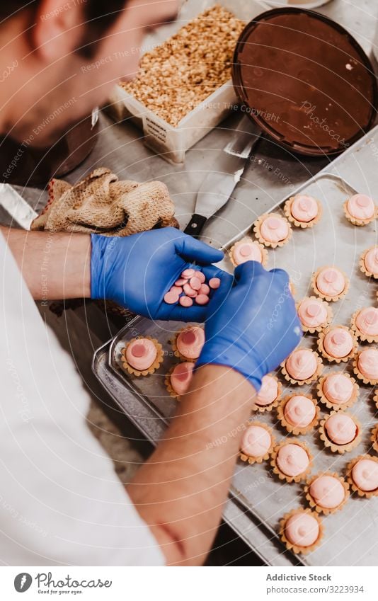 Anonymous baker decorating small cakes confectioner bakery pastry work quality food traditional man preparation production small business occupation patisserie
