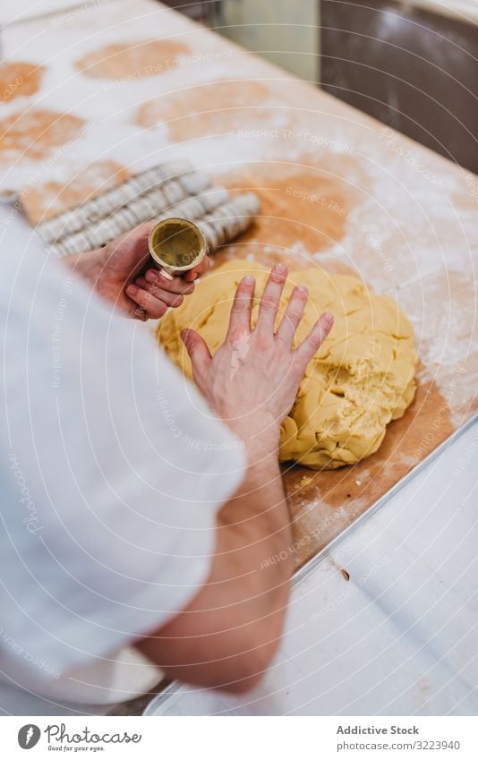 Bearded confectioner putting dough into cup bakery table kitchen pastry preparation fresh man raw cuisine professional food chef restaurant cafe cook recipe