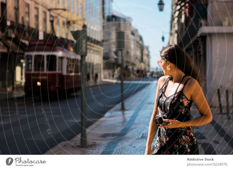 Woman holding a camera while standing on street woman town travel casual confident picture scenic lisbon portugal sunny city photographer young taking photo