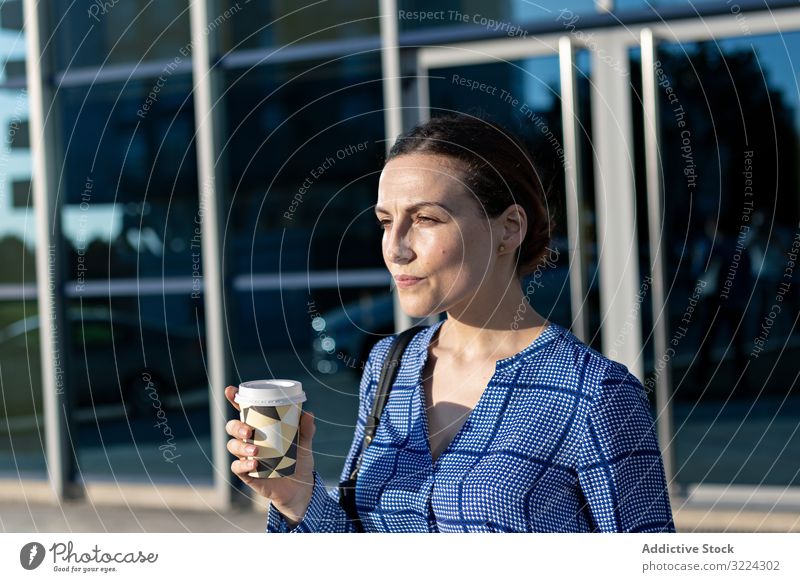 Businesswoman drinking on city street businesswoman building modern coffee to go elegant female serious beverage tea hot takeaway cup contemporary town