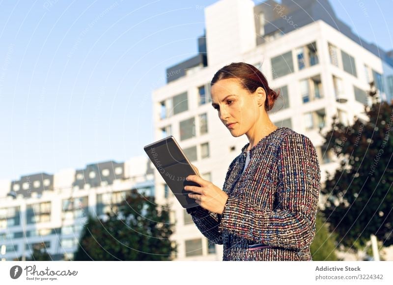 Confident entrepreneur with tablet on city street businesswoman using building serious confident sunny daytime female urban work job internet device gadget lady