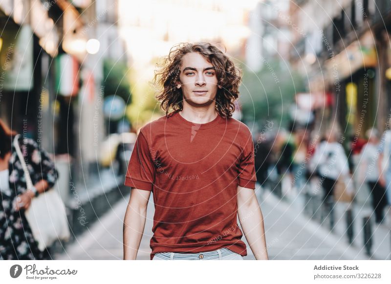 Dreamy modern man walking along city street dreamy casual t shirt handsome urban pensive stroll summer asian ethnic young adult town relaxed determined