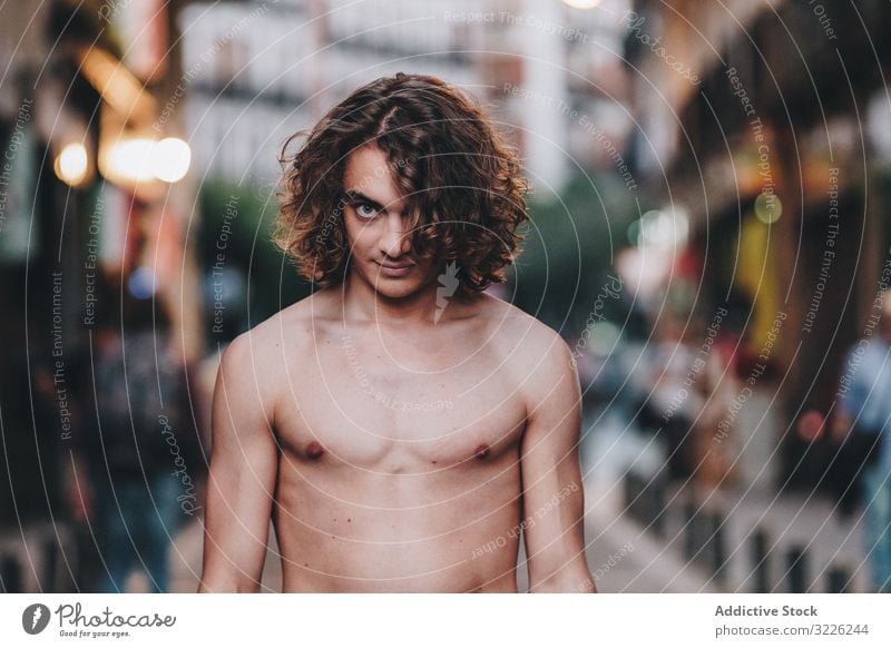 Sensual man gazing and standing shirtless on street sensual gaze confident pensive naked handsome urban long hair young adult day desire passion sexual body