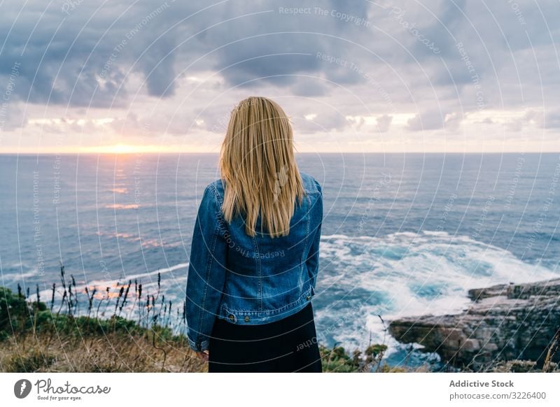 Woman on seashore against dusky clouds woman horizon seascape sunset harmony contemplation overcast chill scenic trip travel ocean tranquil recreation twilight