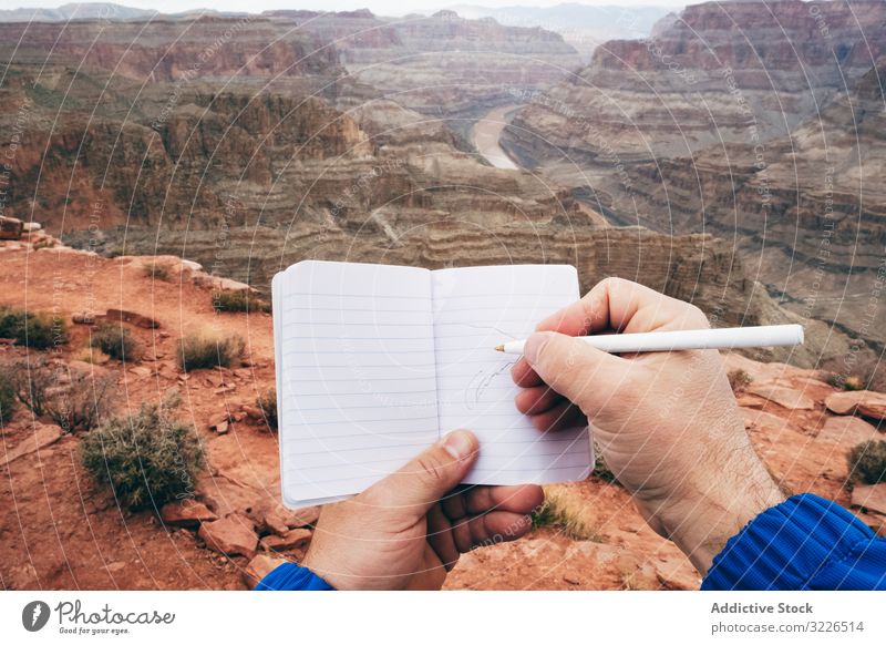 Male drawing in notebook at rock man canyon cliff edge diary rest male usa nature travel landscape hiker terrain tourist grand park adventure national extreme