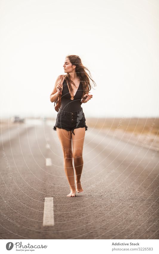 Smiling woman walking on road attractive empty stylish young happy direction elegant lifestyle beautiful female adventure travel casual freedom urban pretty