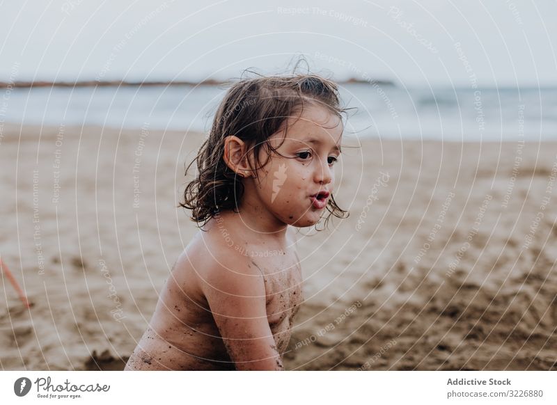 Inspired child playing with sand on beach summer vacation smeared digging holiday fun mouth girl game enjoyment expression activity cheerful joyful small