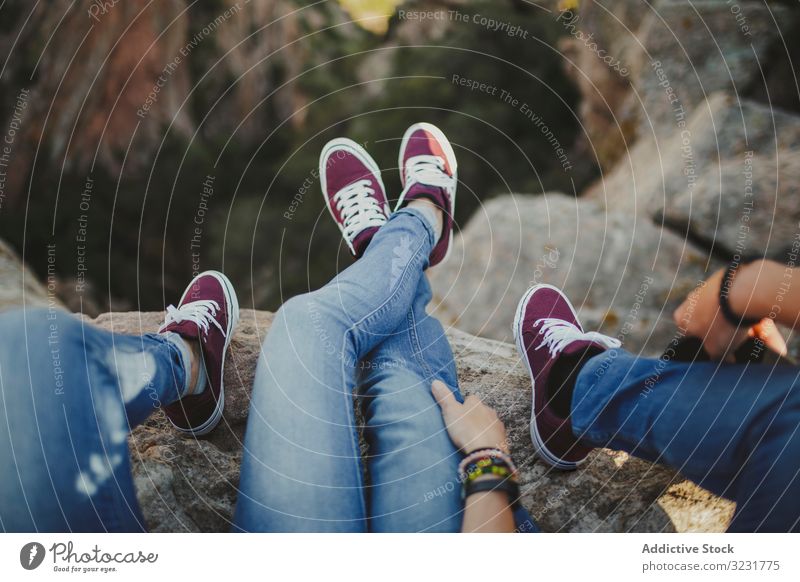 Casual couple resting together while sitting on high cliff mountain embrace romantic feet similar hilly happy leg edge match identical close adult recreation