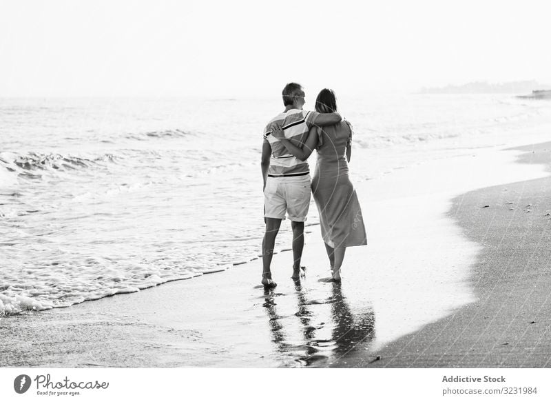 Adult couple walking towards sea beach sand wave resort together holding hands vacation man woman adult barefoot honeymoon weekend water ocean happy holiday