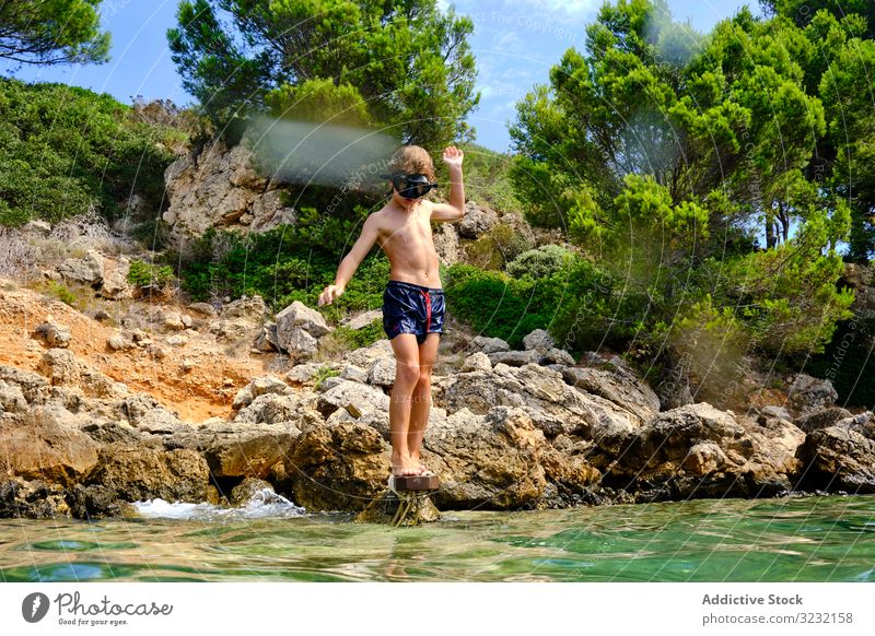 Little boy getting ready to jump in water sea dive summer seashore balance child mask coast travel active rocky tourism cliff sporty recreation wet energy