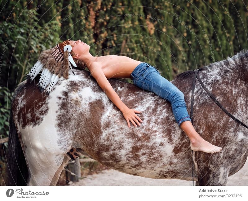 Peaceful child daydreaming while lying on horse boy harmony authentic war bonnet horseback love kind indian costume meditation innocence inspiration caress