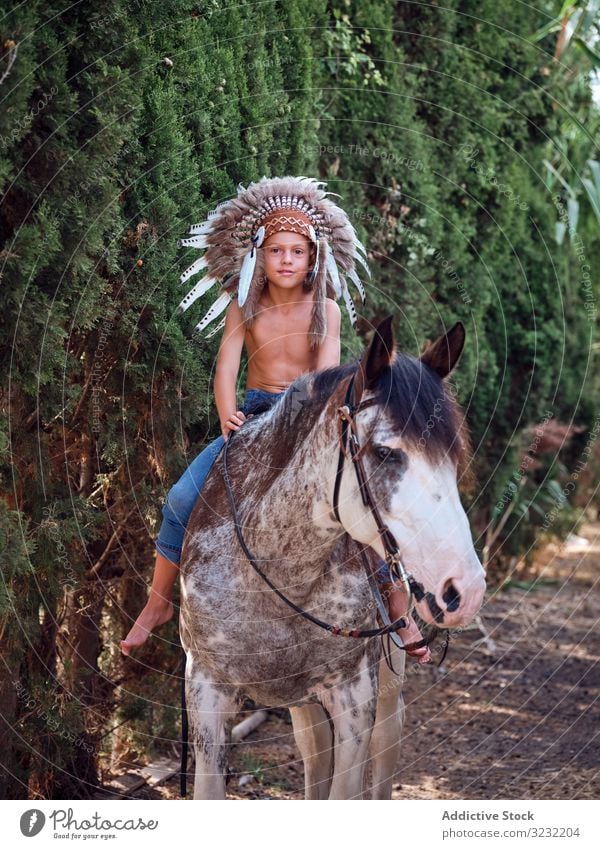 Concentrated child saddling stallion boy horse ride authentic saddle war bonnet indian costume training concentrated native art headdress head wear hat feather