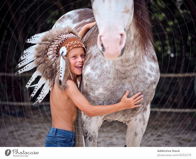 Tender boy hugging horse at farm bonding child tender authentic harmony war bonnet kind stallion indian love touch costume caress concentrated stroke shirtless
