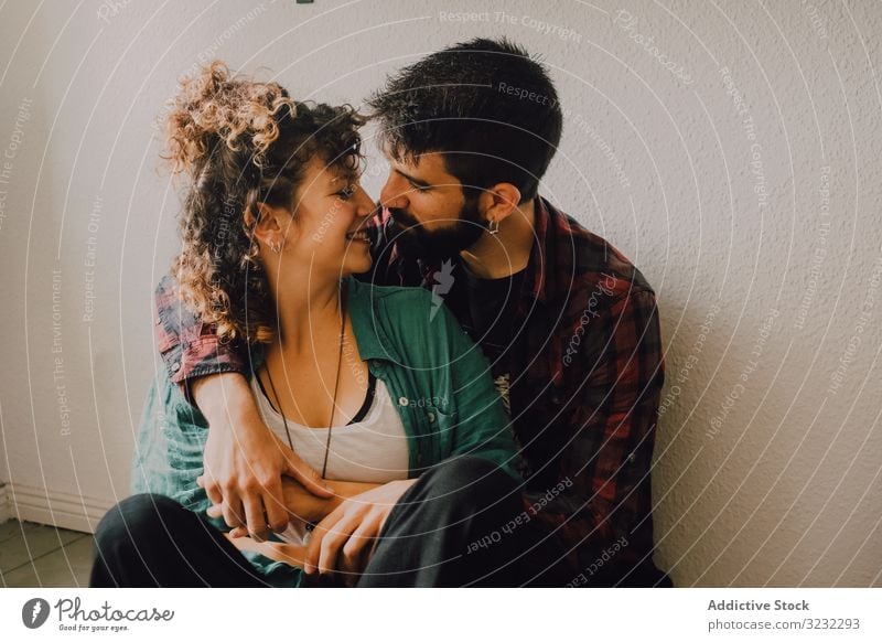 Happy couple embracing on wall at home embrace happy joyful smile casual hug hipster modern tender affection lover relationship together lifestyle cheerful